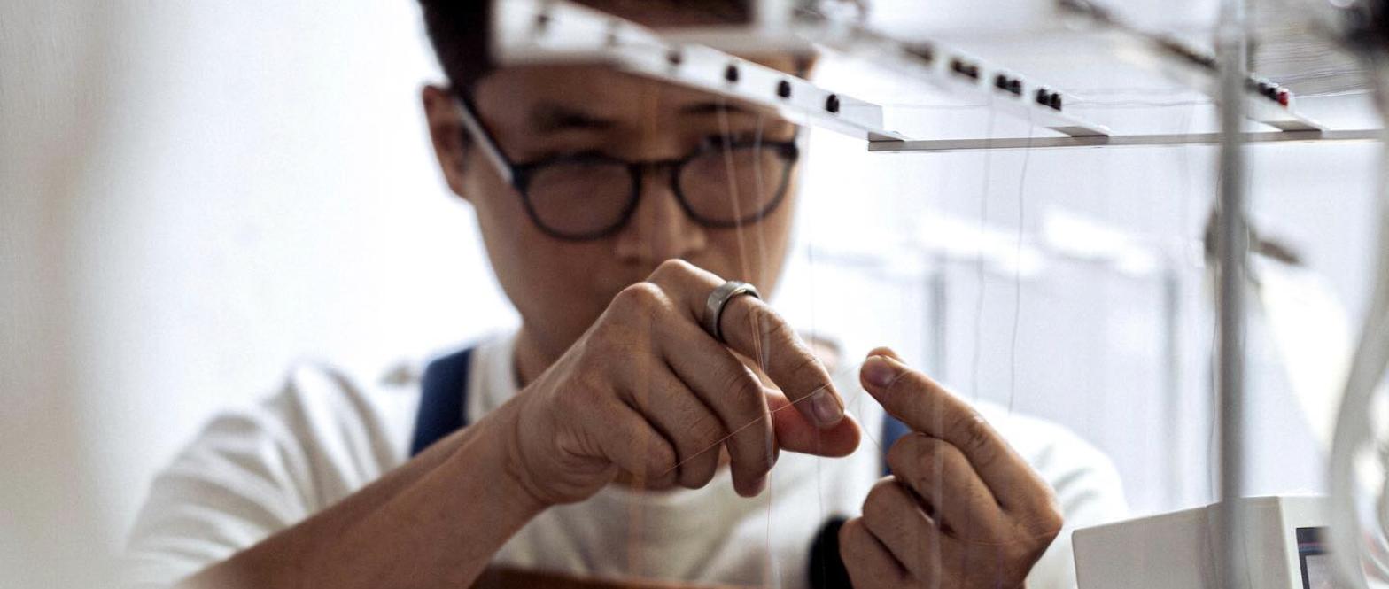 Michael Hsu threading an embroidery machine needle at Sleek Attire in Tampa